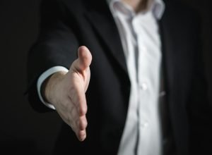 Close-up of a businessman extending hand for a handshake, symbolizing agreement and partnership.